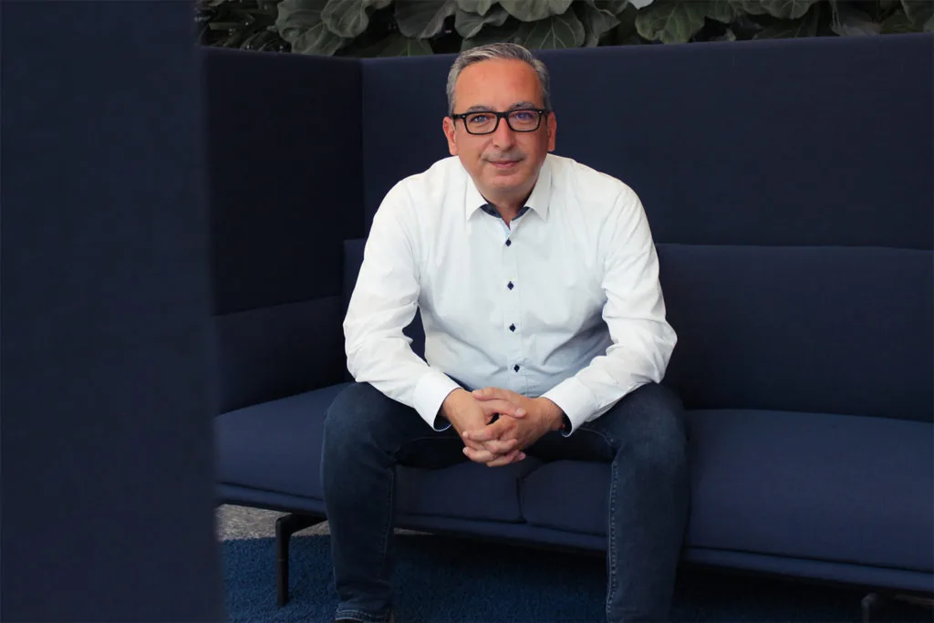Tamer Celikiz sitzt auf blauer Couch